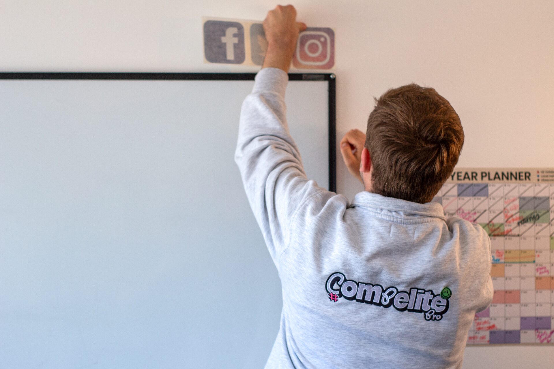 Compelite Pro team member applying social media branding stickers in the office