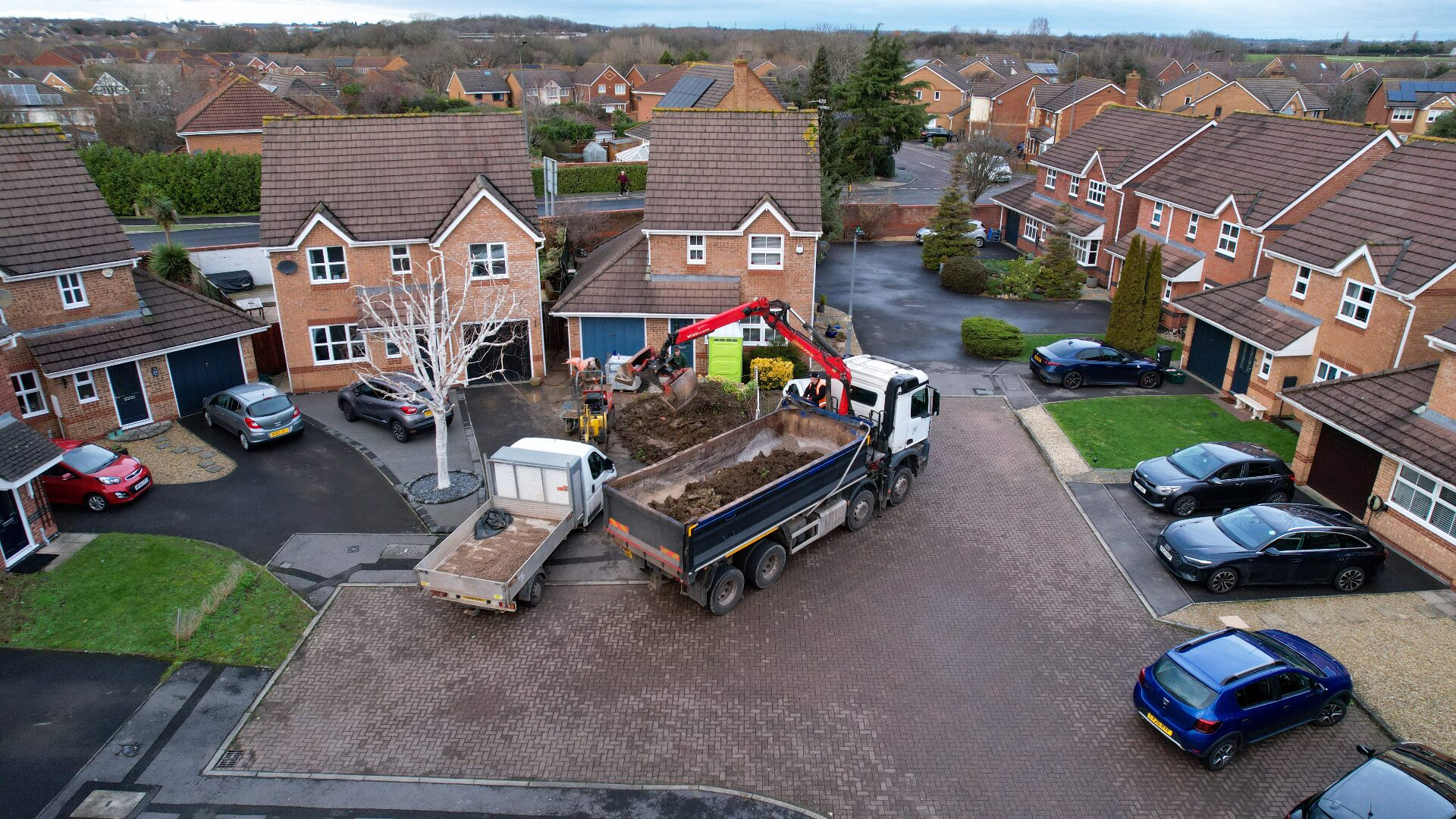 Vivid Scapes landscaping crew on-site with tipper truck and excavator working on a residential driveway project