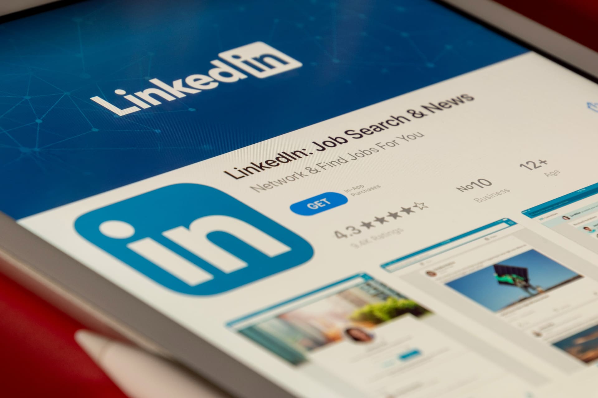 Close-up of a tablet screen showing the LinkedIn app in the App Store on a red background — LinkedIn marketing and professional positioning