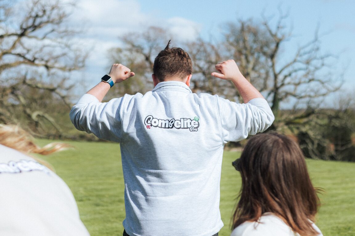 Compelite Pro team in branded sweaters celebrating in a sunny field