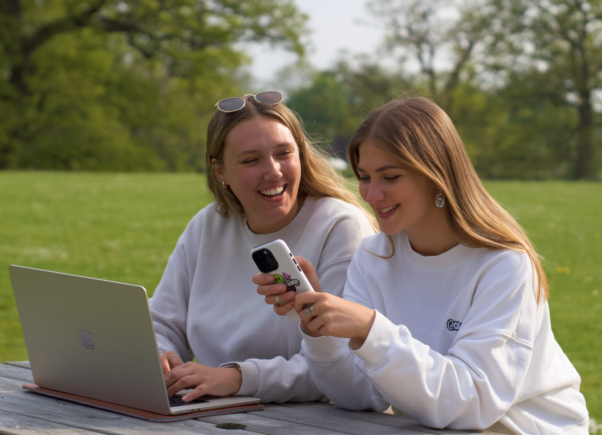 Compelite Pro team laughing while reviewing a client's social content together at a park picnic table in Bristol