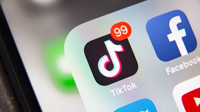 Close-up of a phone home screen showing the TikTok app icon with 99+ notifications next to Facebook — TikTok marketing and content strategy